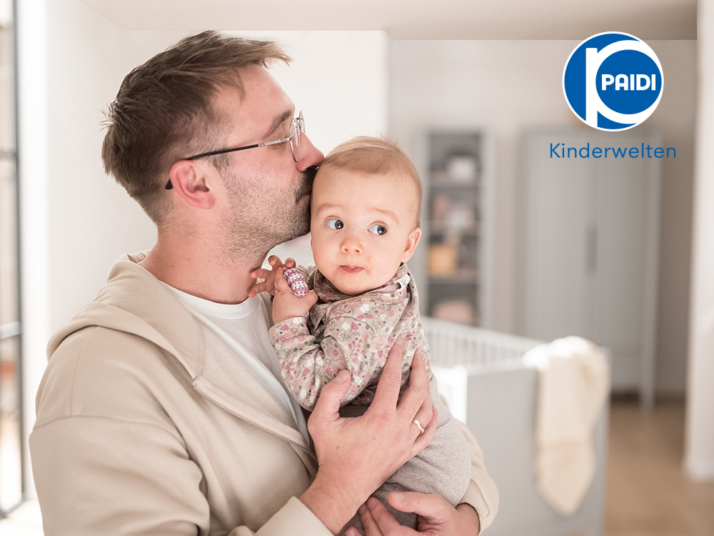 Ein mann, der ein baby in seinen armen hält.