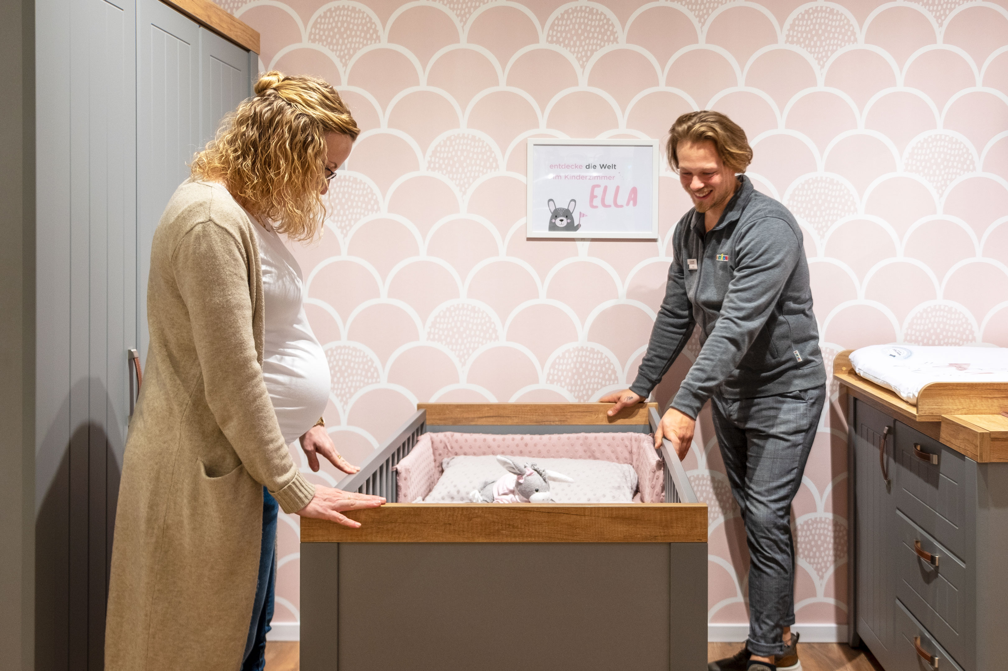 Eine frau, die neben einem baby in einem kribbeln steht.