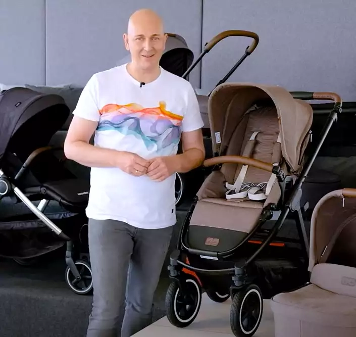 Ein mann in einem weißen hemd steht neben einer babykutsche.