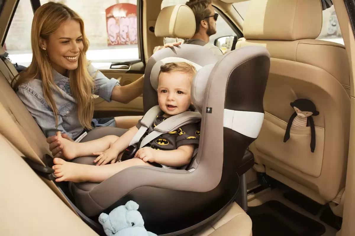 Eine frau, die ein baby auf einem autositz hält.